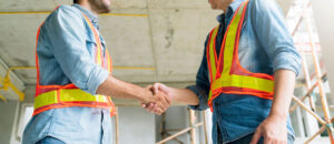 Two Civil Engineer or Architect wearing helmet and handshaking together .architecture and home renovation concept - builder at site construction shaking partner hand with confident
